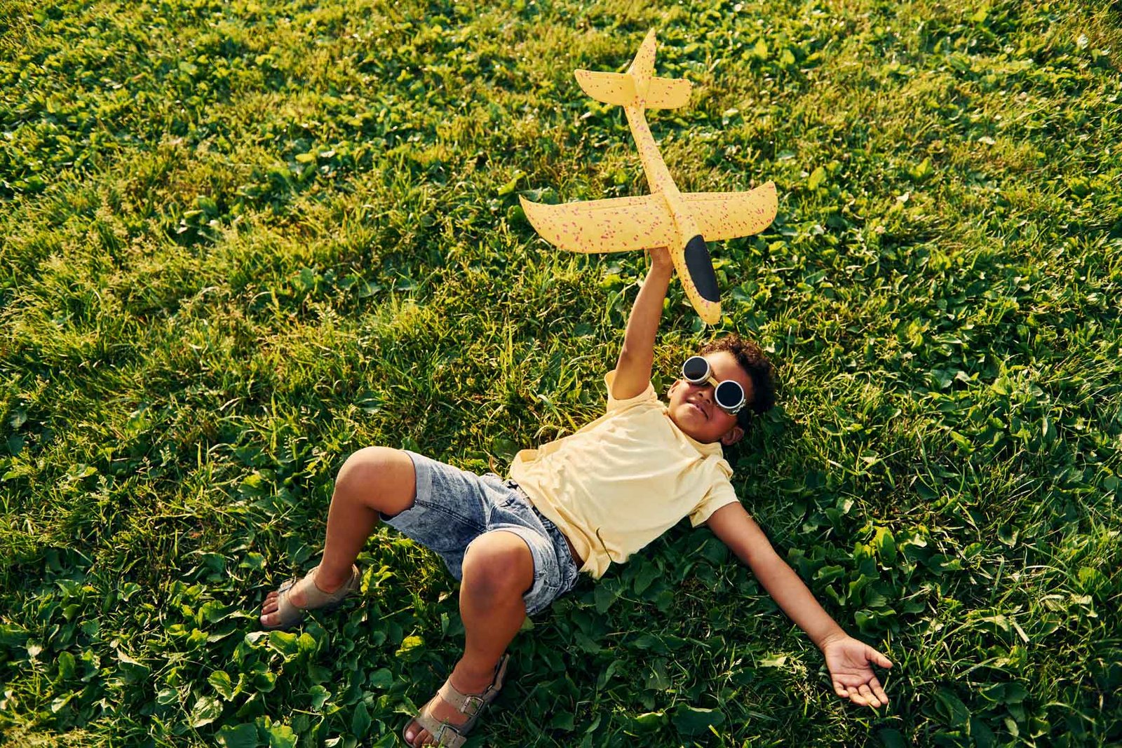 Enfant qui joue avec un avion jeune dans le jardin