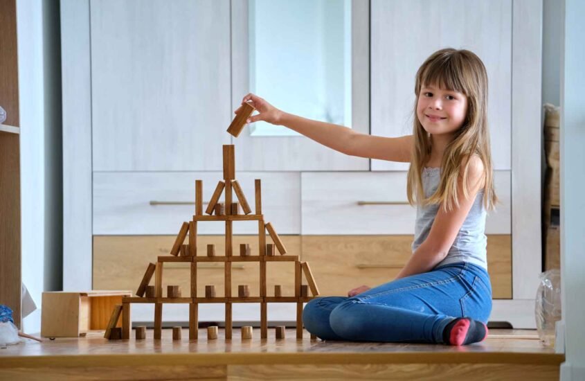 Jeune fille qui construit avec jouet en bois de construction une jolie pyramide