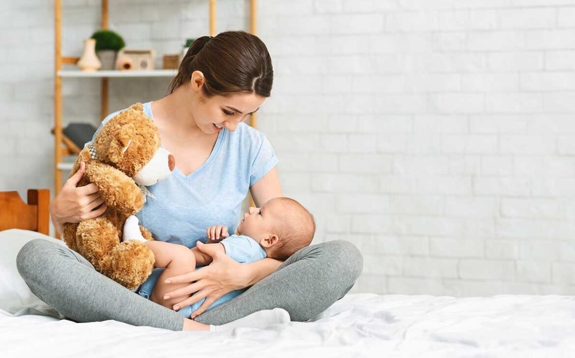 Jeune Femme qui joue avec un nouveau-né et un ours en peluche