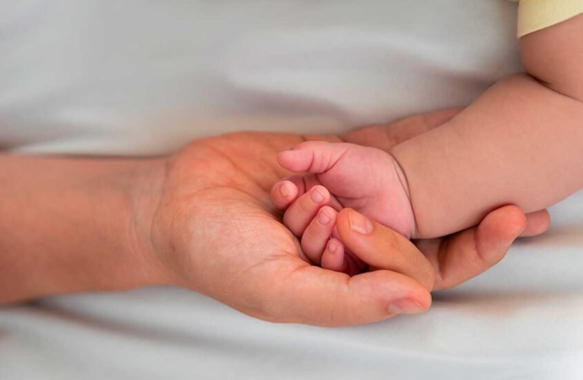 Main d'un adulte tenant dans sa paume la main d'un nouveau-né