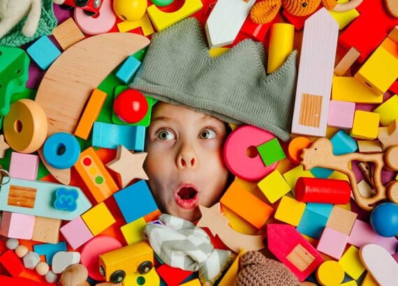Visage étonné qui immerge d'une pile de jouets en bois aux couleurs vives