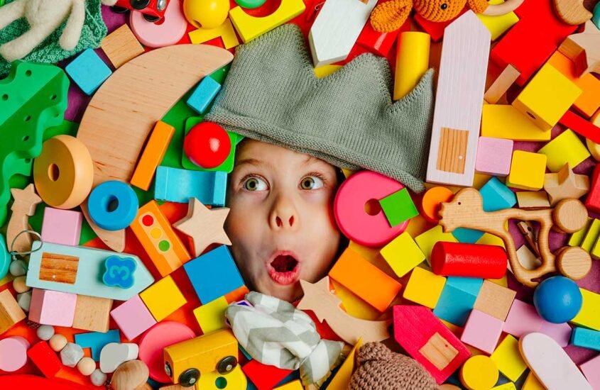Visage étonné qui immerge d'une pile de jouets en bois aux couleurs vives